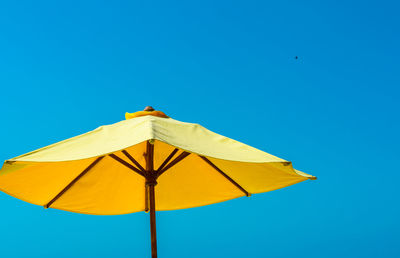 Low angle view of umbrella against blue sky