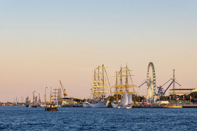 Boats in sea against clear sky during sunset