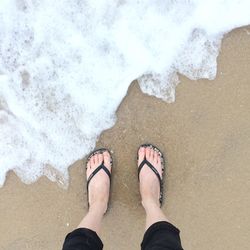 Low section of man standing on beach