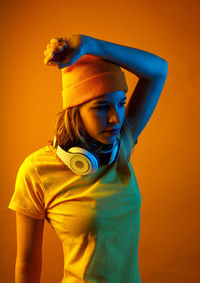 Portrait of woman standing against yellow background