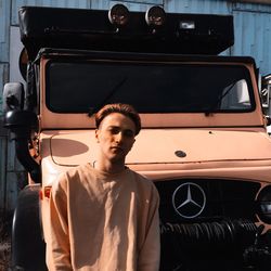 Portrait of young man standing in car