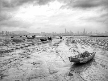 Boats moored at harbor in city against sky