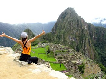 Rear view of excited woman with arms outstretched looking at historic machu picchu