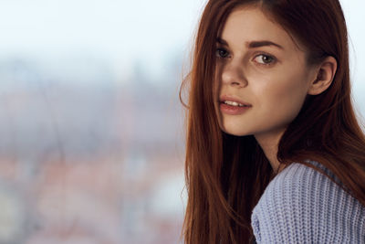 Portrait of young woman standing against sky