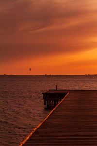 Pier over sea against orange sky