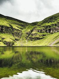 Idyllic shot of green mountain reflection in lake