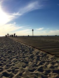 Boardwalk at sandy beach against sky