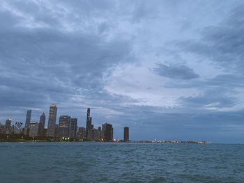 Sea by modern buildings against sky