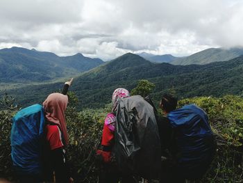 Rear view of people on mountain against sky