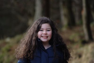 Portrait of smiling young woman standing in forest