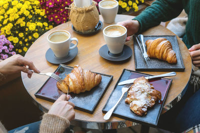 High angle view of breakfast served on table and two women hands