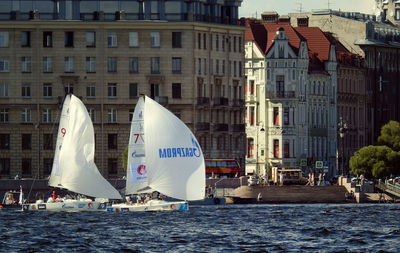Sailboats in city against buildings