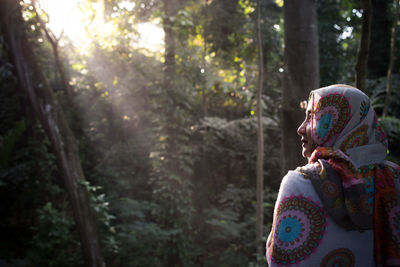 Woman wearing hijab while standing in forest