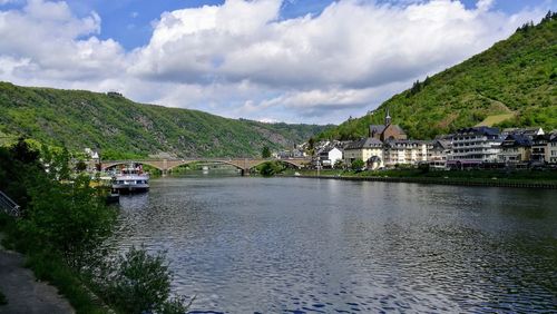 Scenic view of river by buildings against sky