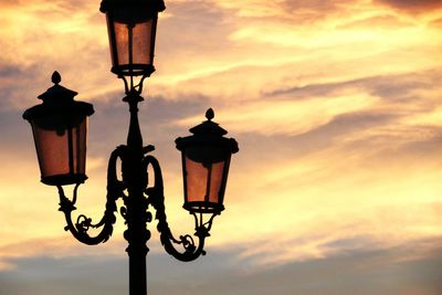 Low angle view of illuminated street light against sky