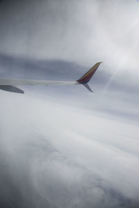 Airplane flying over clouds against sky