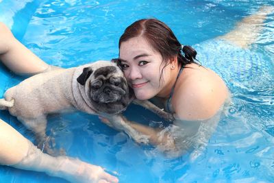 Portrait of young woman with dog in swimming pool