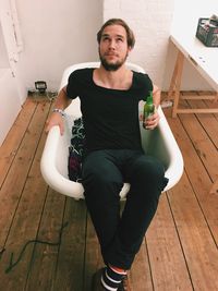 Man sitting in bathtub while holding beer bottle