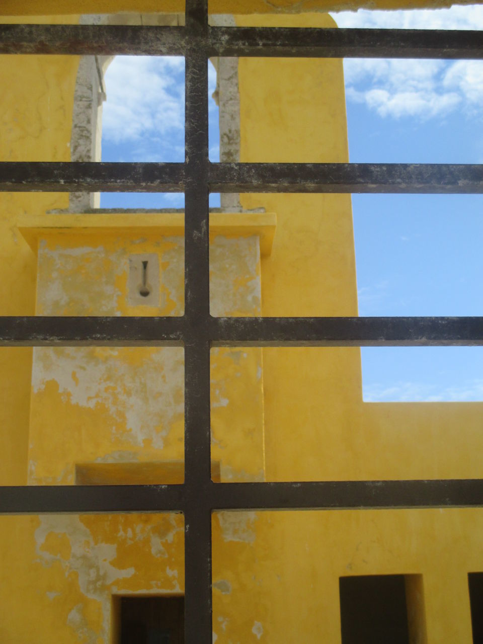 FULL FRAME SHOT OF YELLOW METAL GRATE AGAINST SKY