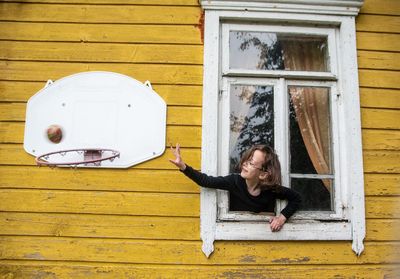 Kid playing with the ball through the window