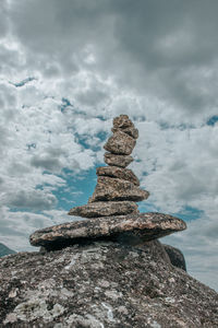 Stack of stones on rock against sky