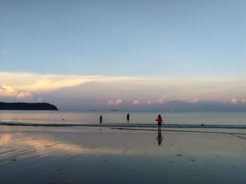 People on beach against sky during sunset