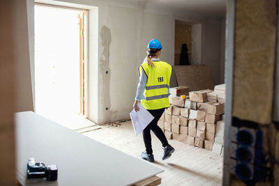 Female manual worker looking at stack of boxes while walking at site