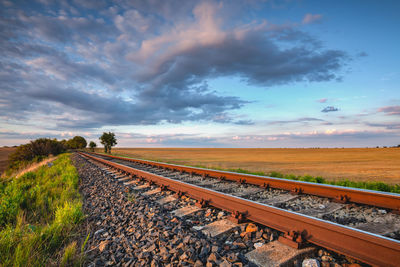 Railroad tracks on field against sky