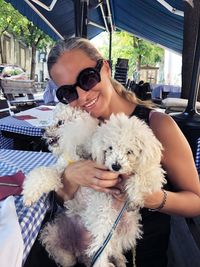 Smiling woman wearing sunglasses carrying dogs in city