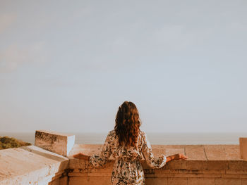 Rear view of woman looking at sea against sky