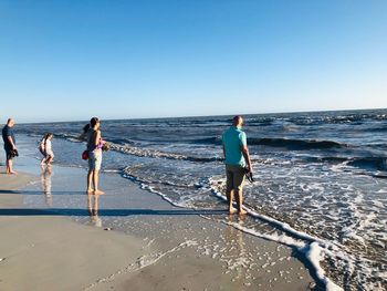 People on beach against clear sky