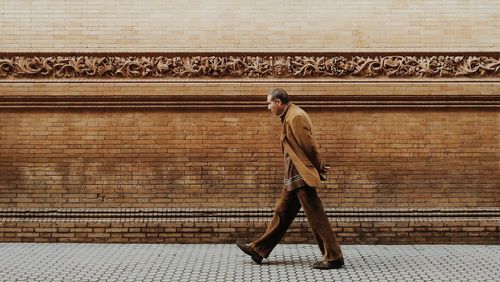 Full length of young man walking on sidewalk