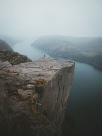 High angle view of person standing on rock formation by lake