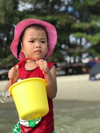 Girl playing with bucket while standing at beach