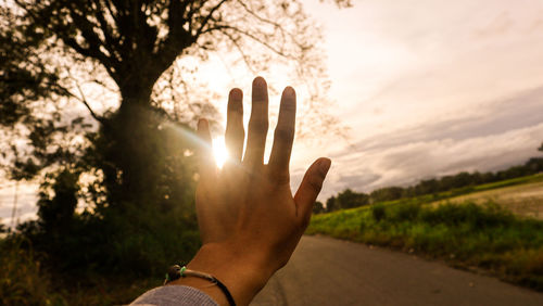 Midsection of person against sun during sunset