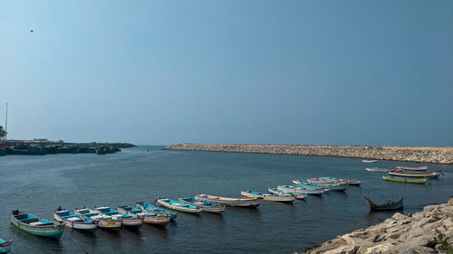 Boats moored in sea against clear blue sky