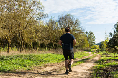 Rear view of man walking on footpath