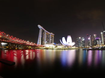 Illuminated city by river at night