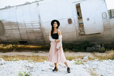 Full length portrait of woman standing against building