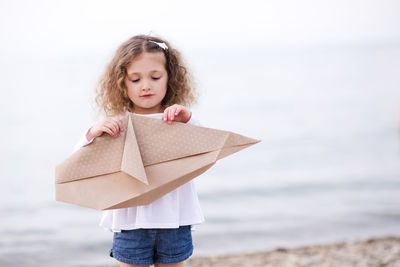Girl making fish with origami paper at beach