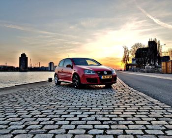 Car on street against sky at sunset