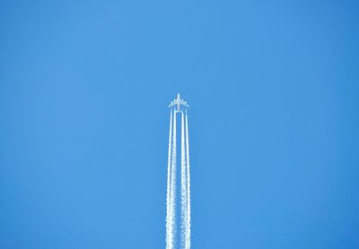 Low angle view of vapor trail against blue sky