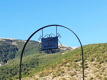 Road sign against clear blue sky