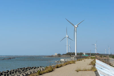 Wind turbines on sea against clear sky