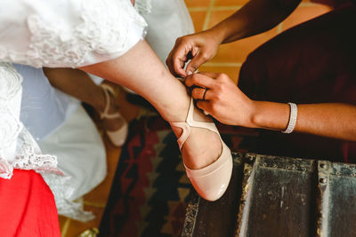 Cropped hands of bridesmaid assisting bride with shoe