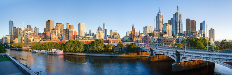 Panoramic view of buildings by river against sky in city