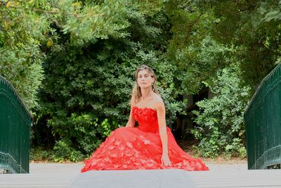 Woman with red umbrella against trees