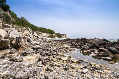 Rock formation on beach against sky