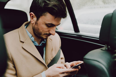 Close-up of businessman using phone while traveling in car