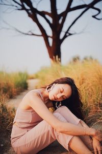 Side view of young woman lying on field against sky